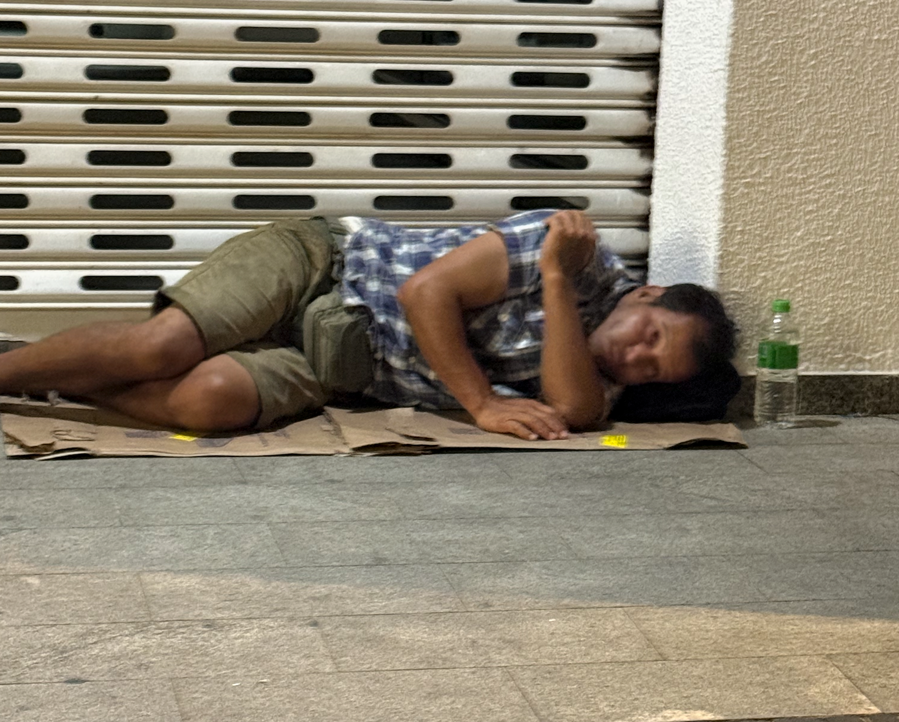 Pessoa deitada sobre papelão na calçada